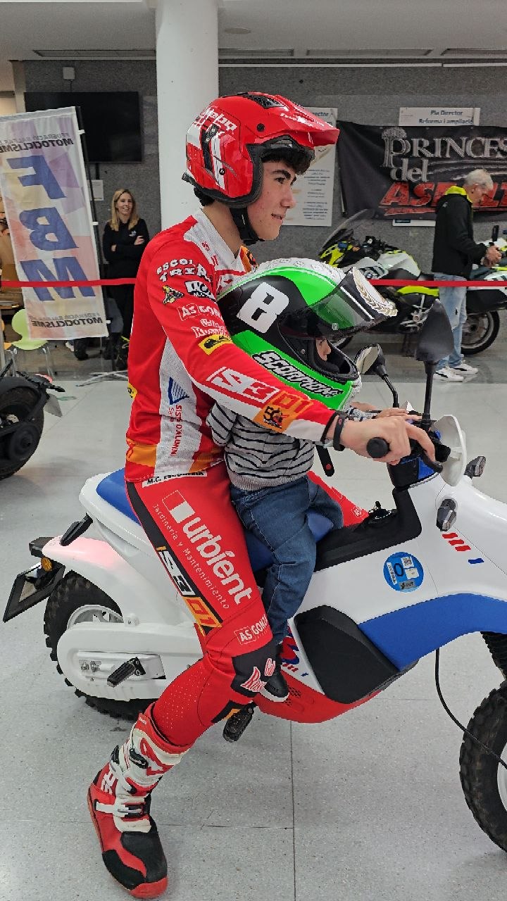 Piloto acompañando a un niño en una moto infantil